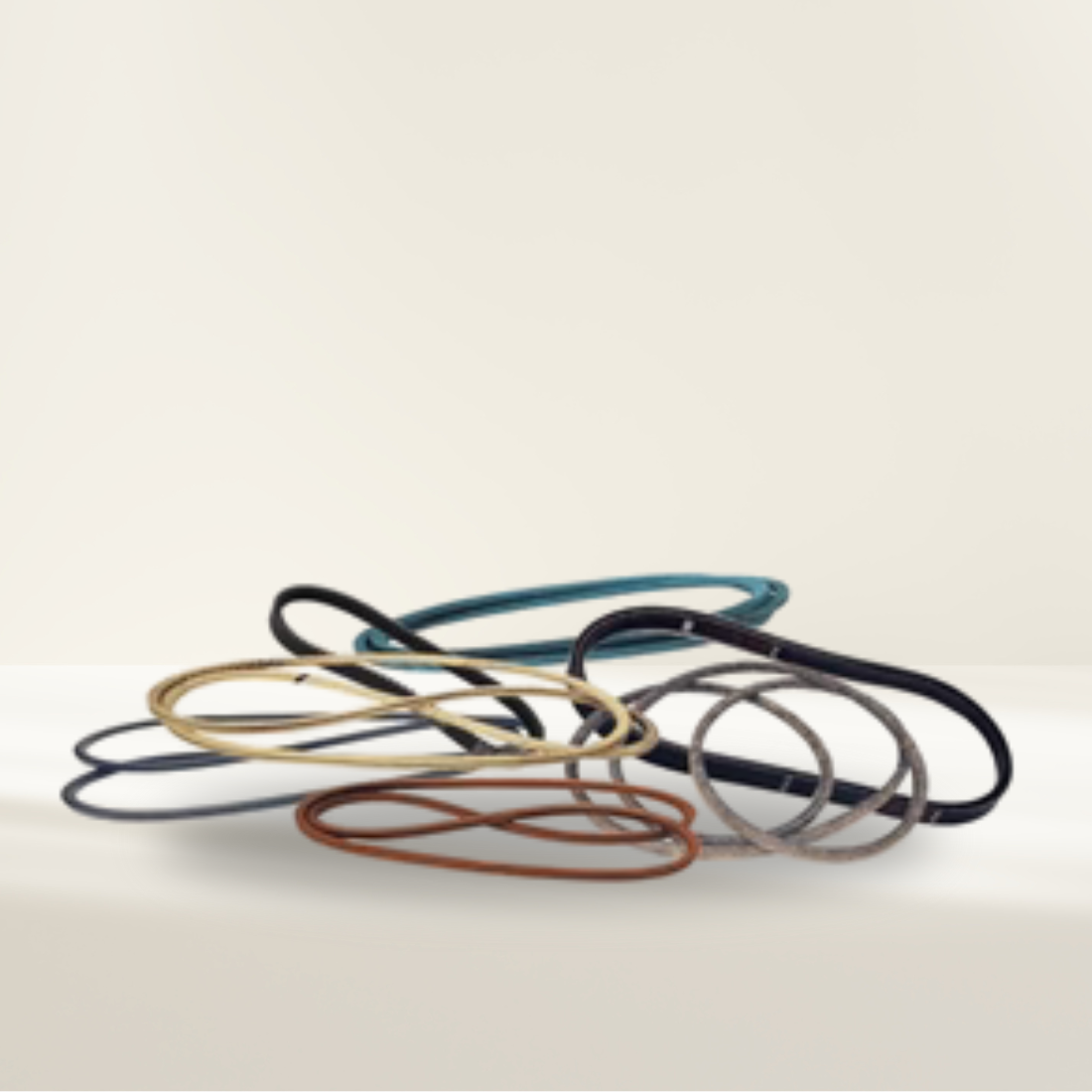 Set of colorful lawn mower belts on a beige background